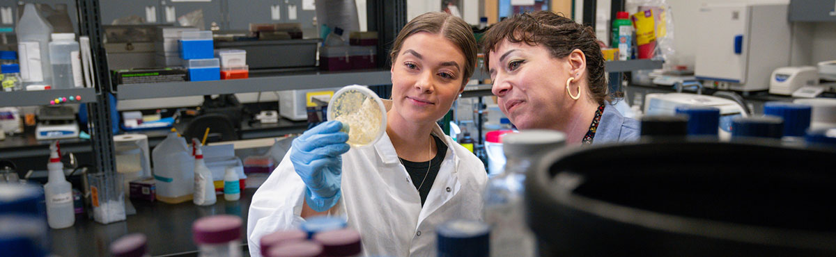 teacher and student in lab looking at petri dish