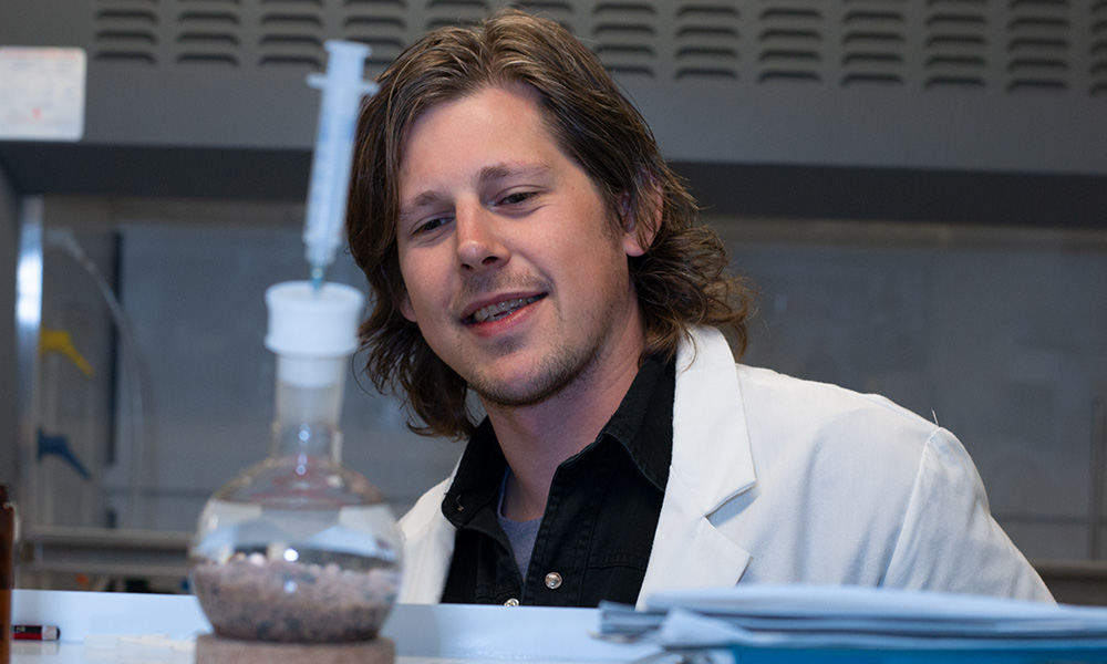 Student in Lab looking at beaker