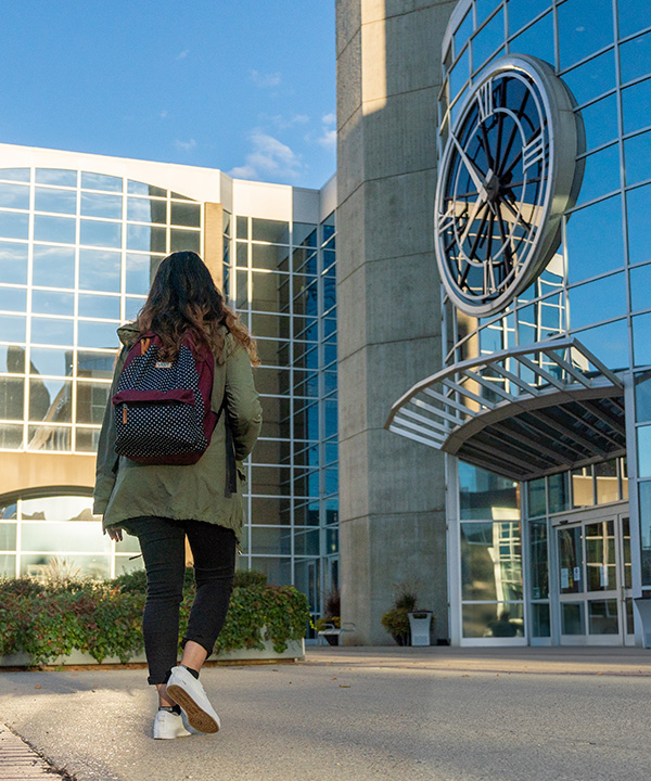 student walking in front of MacEwan clock tower