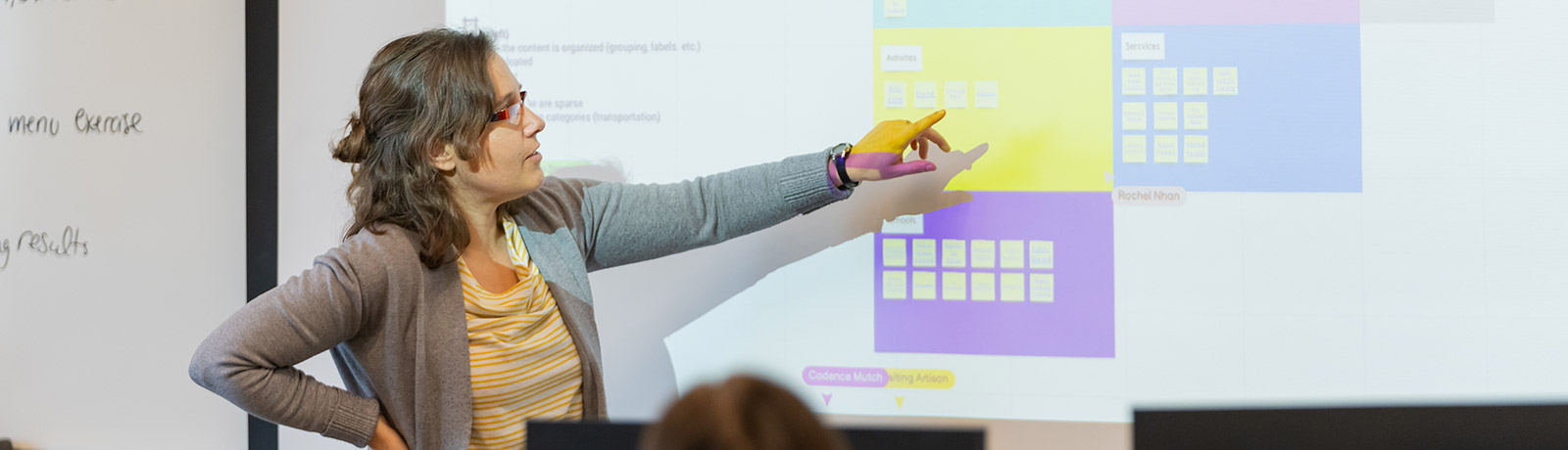 instructor pointing at screen in front of class