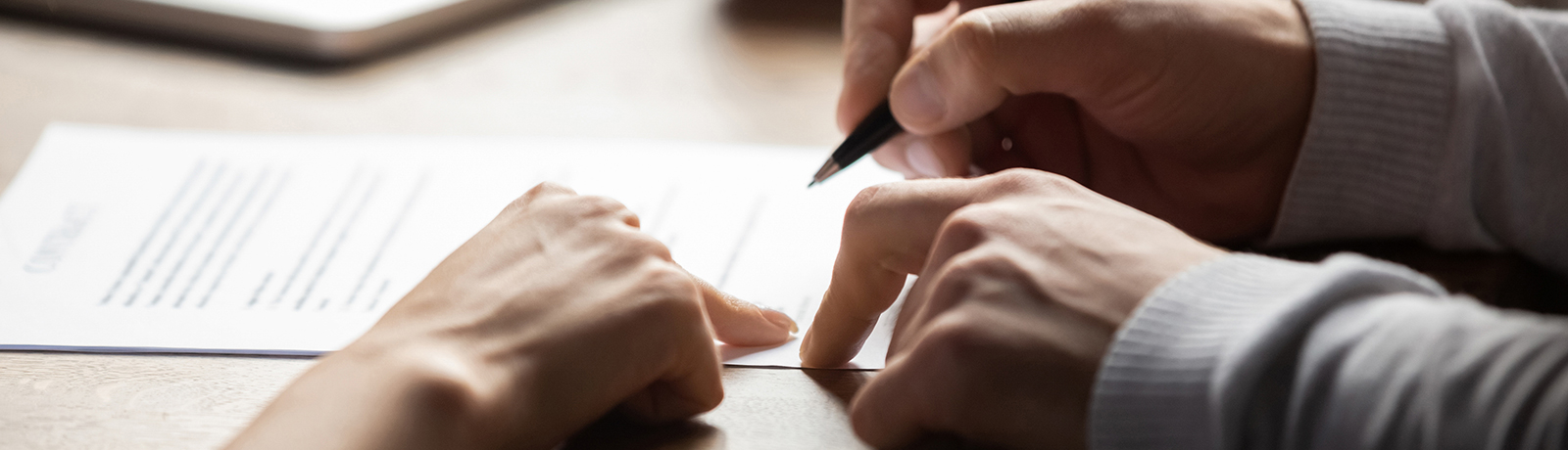 close up of hands on table signing document