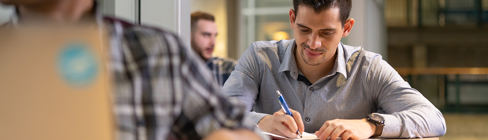 male student writing at desk