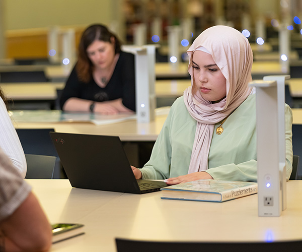 female student studying on laptop in library