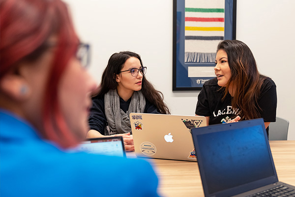 students speaking with laptops in front of them