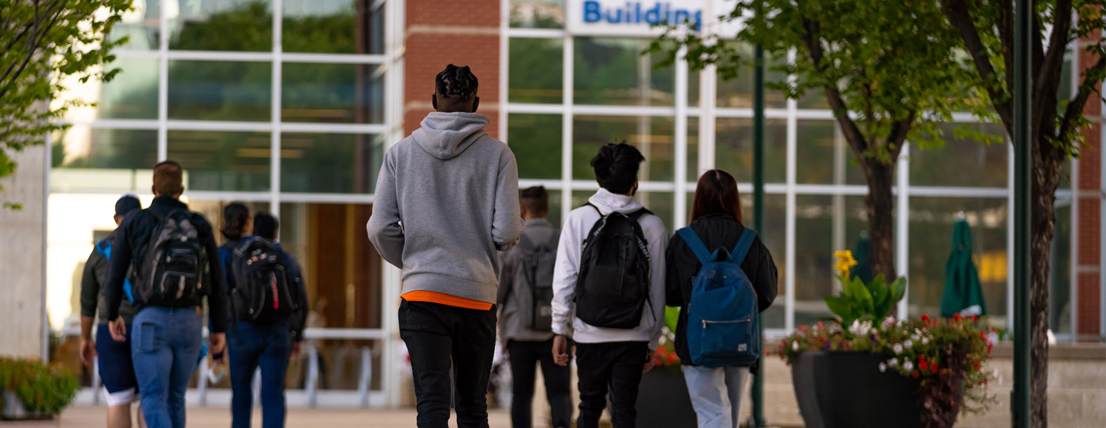 Students outside walking toward the front doors of Building 6 on MacEwan's campus