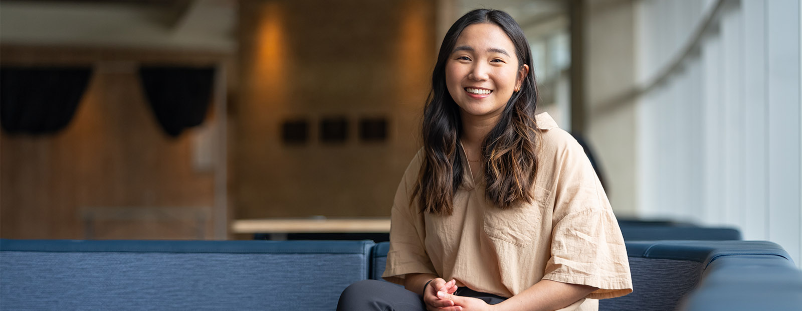 Kathy Kim sits on a sofa on campus