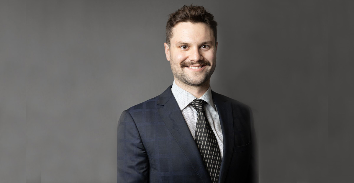 Chris Wray stands in front of a grey backdrop, smiling.