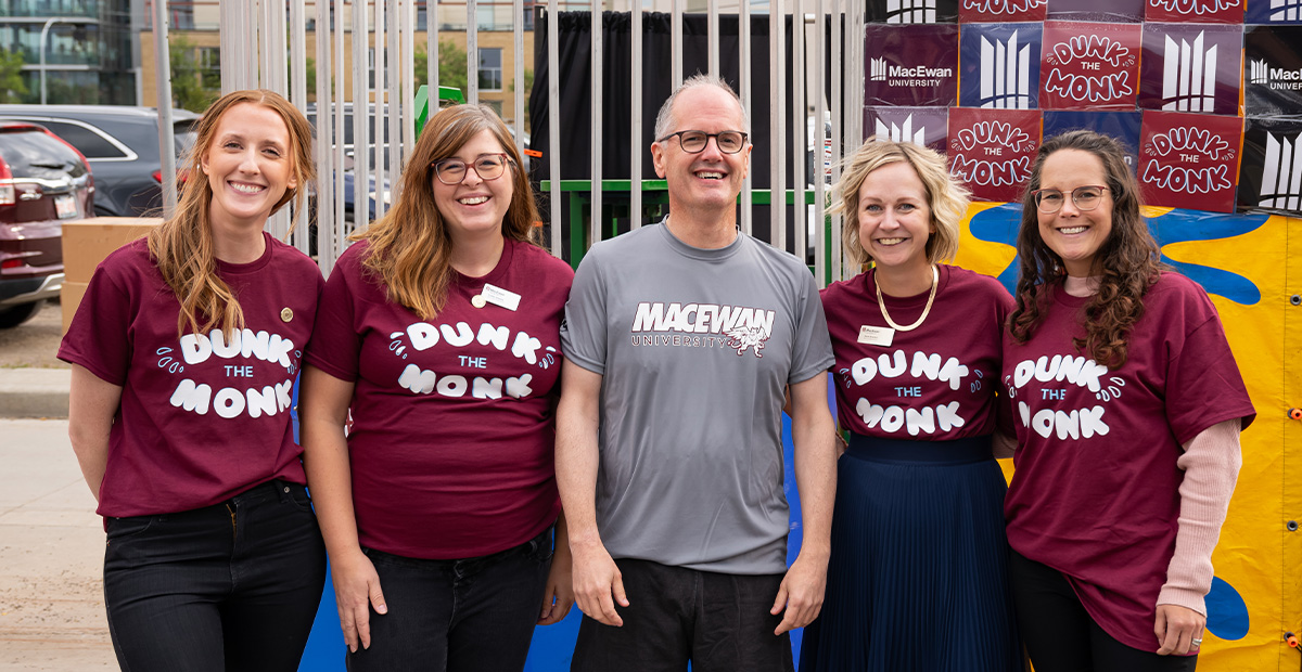 Dr. Craig Monk, MacEwan's provost and vice-president, poses with staff in front of a dunk tank for the "Dunk the Monk" event.