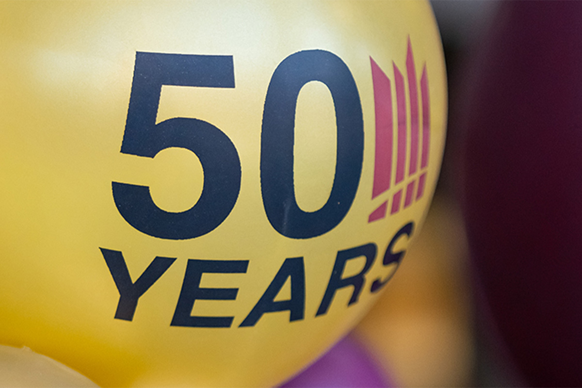 A yellow balloon with the number 50 on it stands out ahead of other plain, maroon and gold balloons