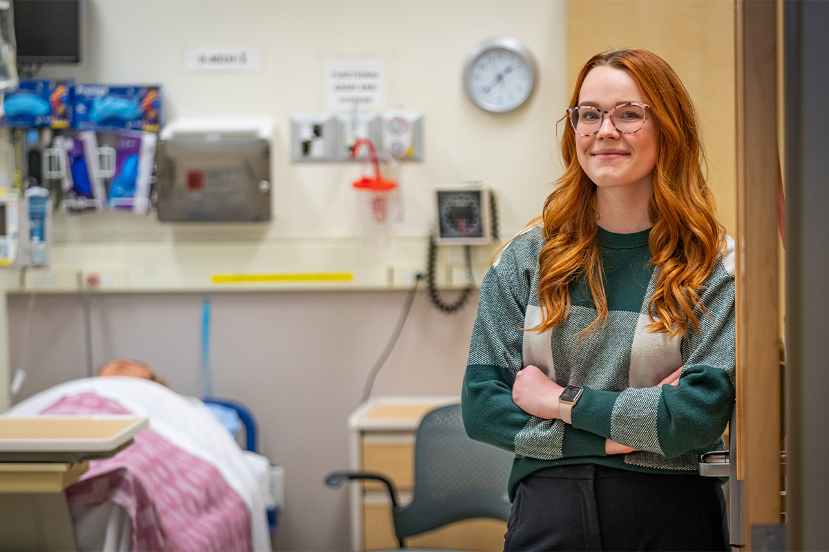 Lena-Marie Voelker, a nursing student, stands in front of a hospital patient room