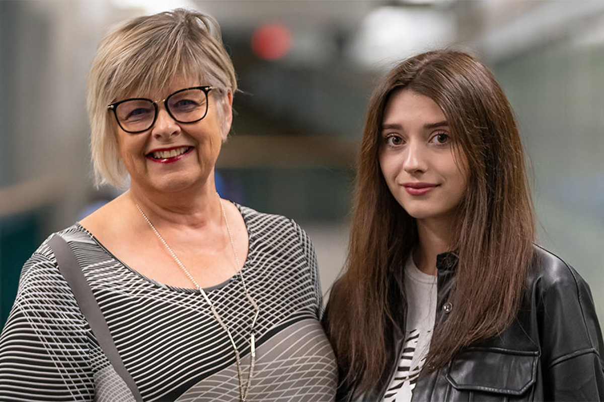 Volunteer instructor Melody Kostiuk and Ukrainian student Anna Berovan pose together in a MacEwan hallway