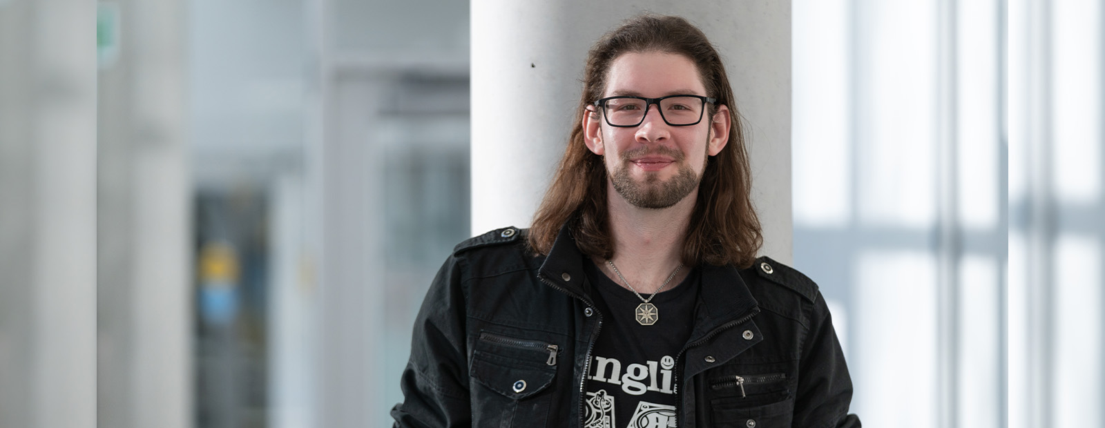 Cole Koch stands in front of a pillar in Allard Hall and smiles