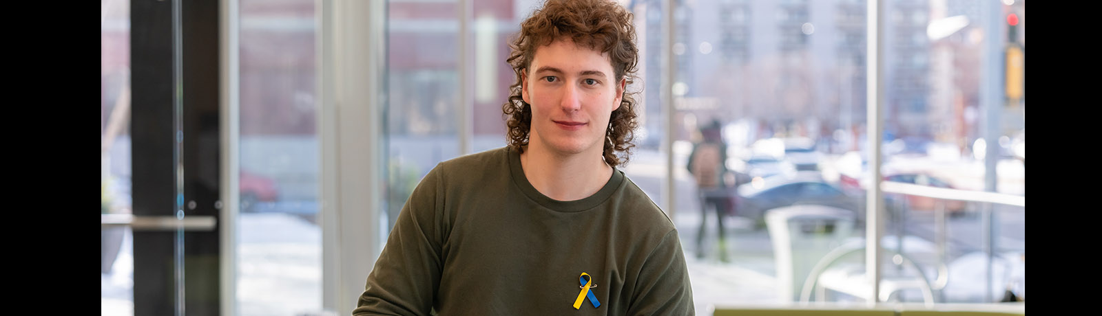 Rory Dumelie stands in the SAMU building wearing a ribbon in the colours of the Ukrainian flag