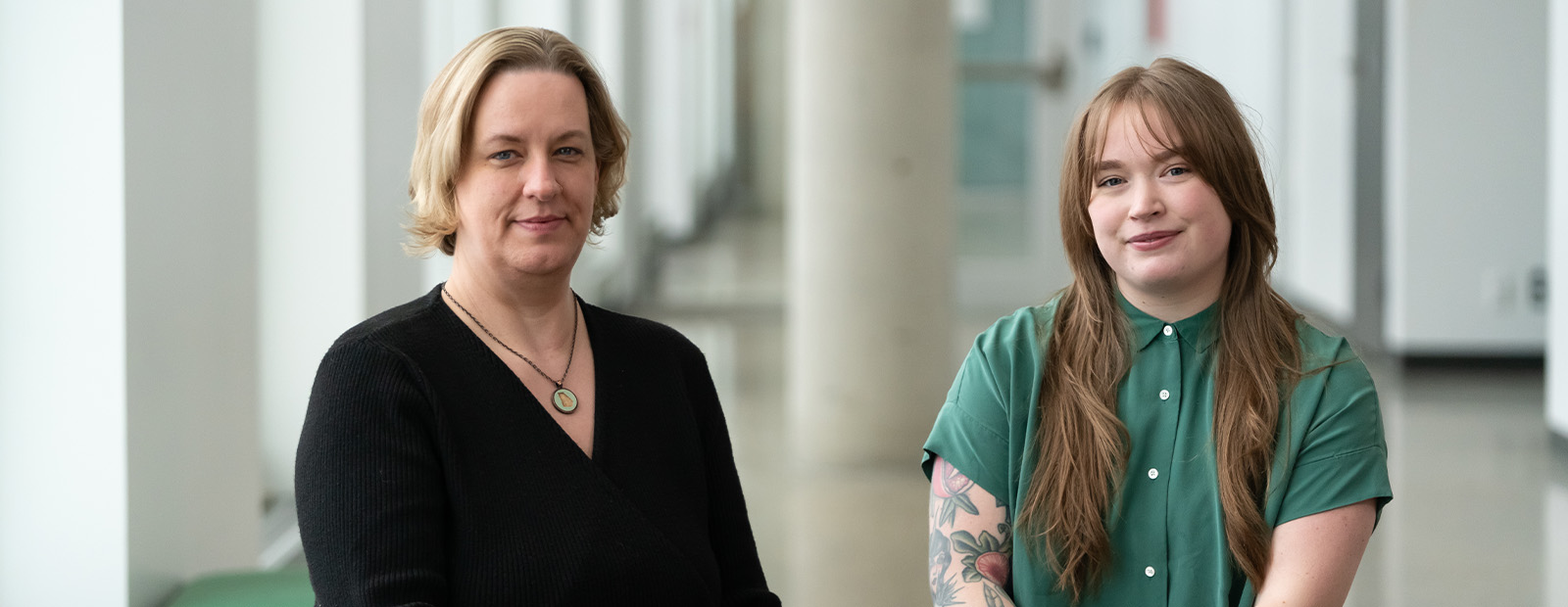 Heather Hutchinson and Elyse Colville sit together on a blue bench in Allard Hall