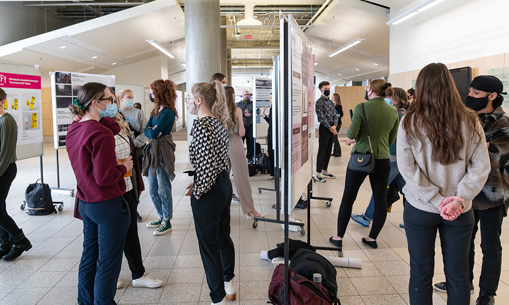 Students standing in front of their poster displays in the Robbins Health Learning Centre.