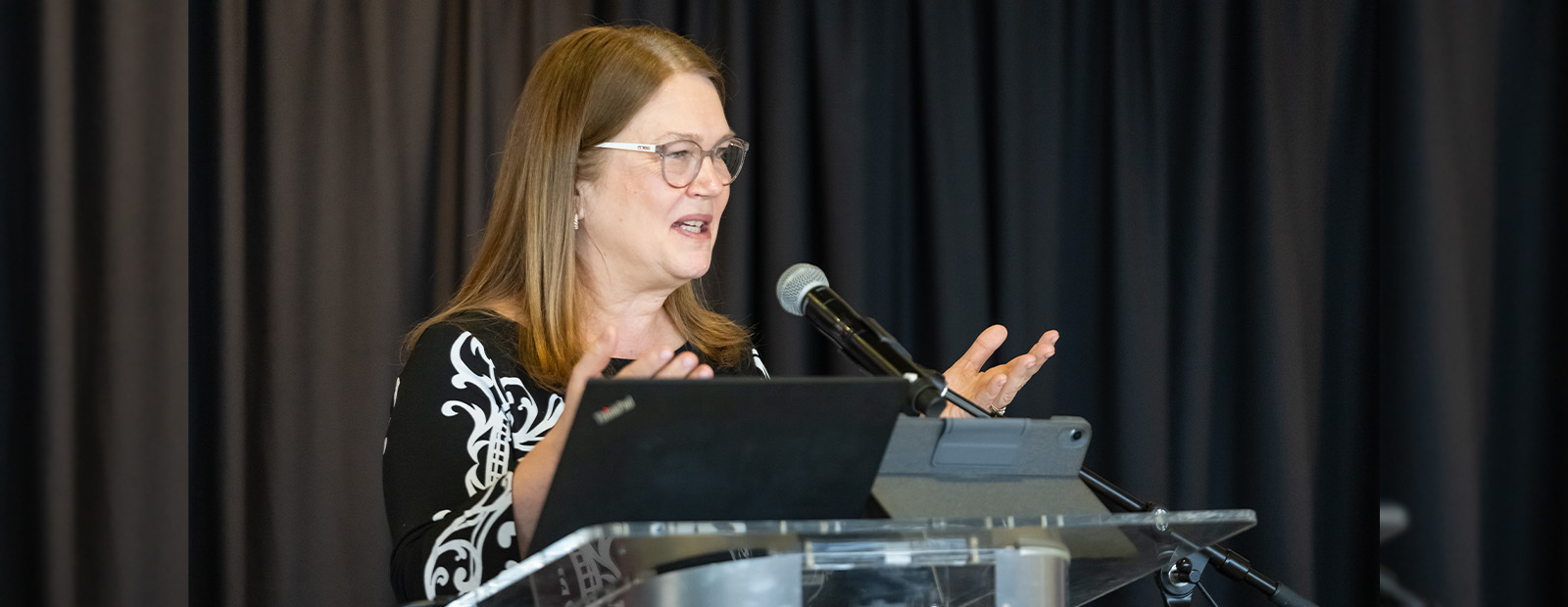 Dr. Philpott stands behind a podium and speaks to a crowd