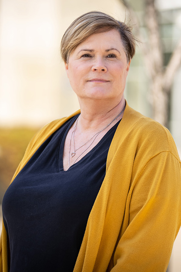 Adine Shuchuk stands outside in a golden yellow cardigan.