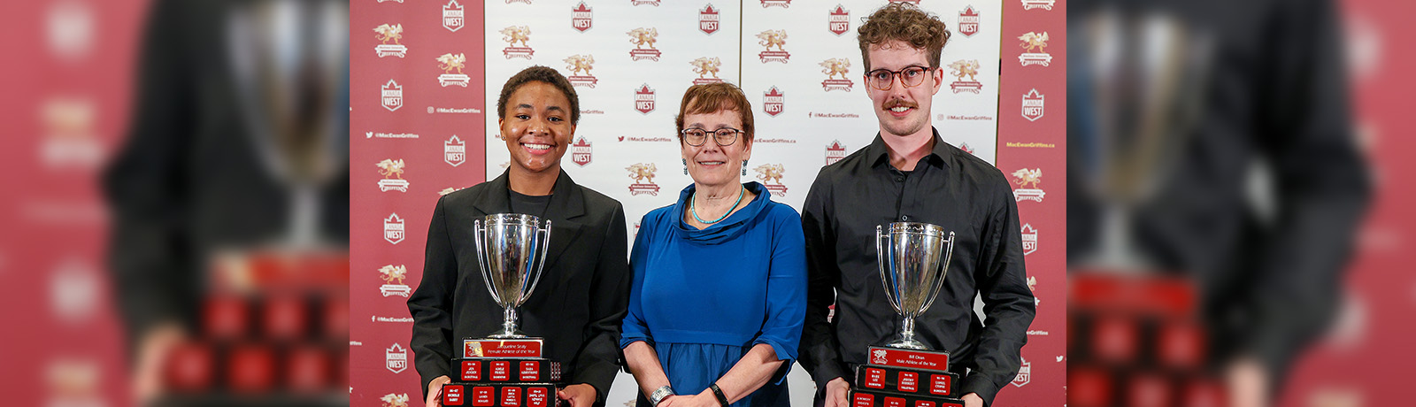 Grace Mwasalla and Ashton Abel hold their trophies while standing alongside university president Dr. Annette Trimbee