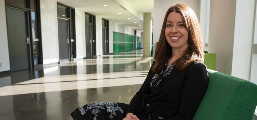 Dr. Copland sits on a green chair in Allard Hall