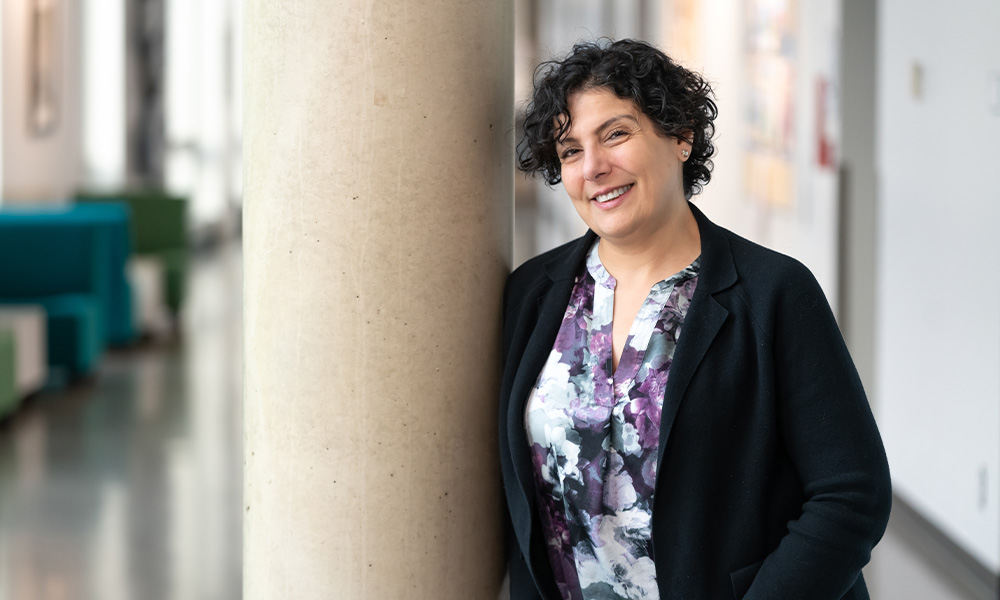 Mona Haimour leans against a concrete pillar and smiles