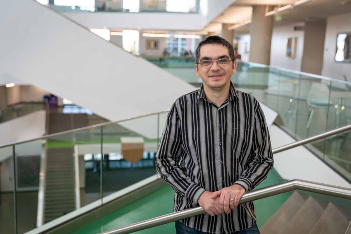 Dr. Nicolae Strungaru stands near the staircase on the second floor of Allard Hall