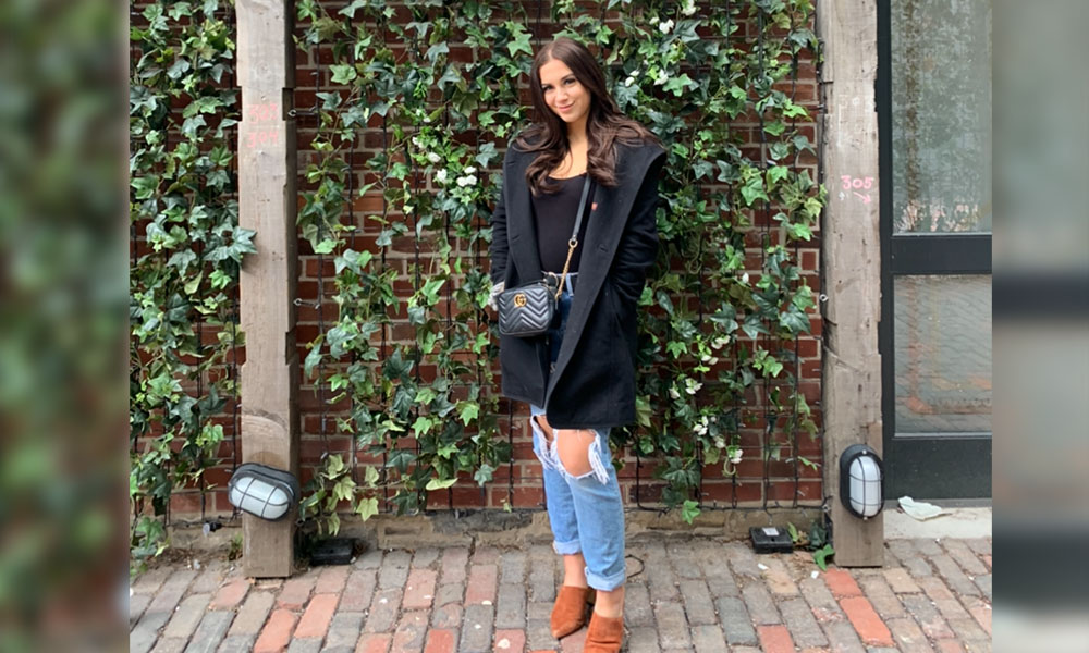 Alysha stands in front of a wall covered in ivy