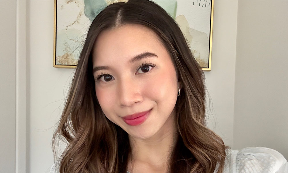 Zinnia smiles in front of a white wall with a painting 