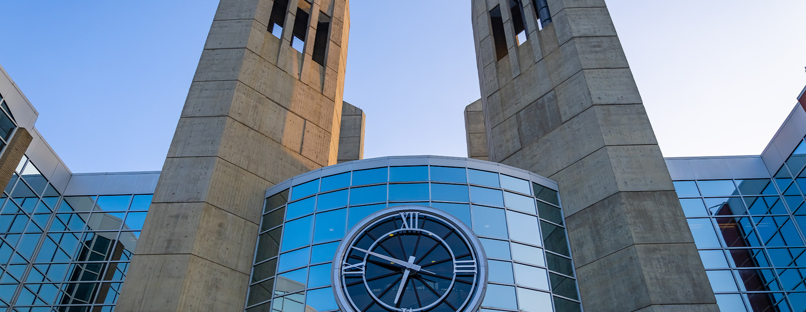 A close-up shot of the clock tower on MacEwan's campus at sunrise