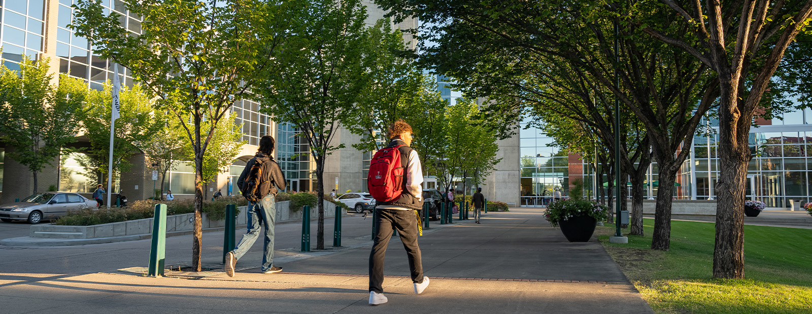 Two students wearing backpacks approach the clocktower door of MacEwan's campus.