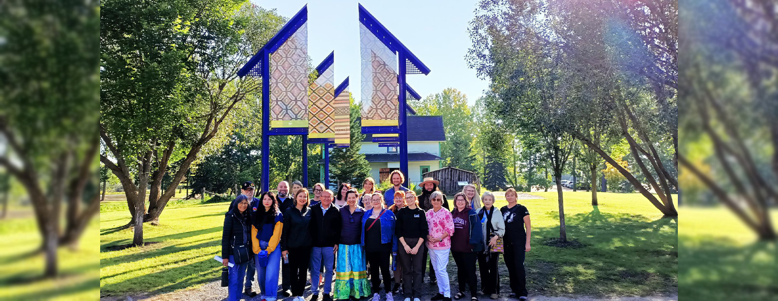 A group of people stand together in front of a welcome sign at the Ukrainian Heritage Village