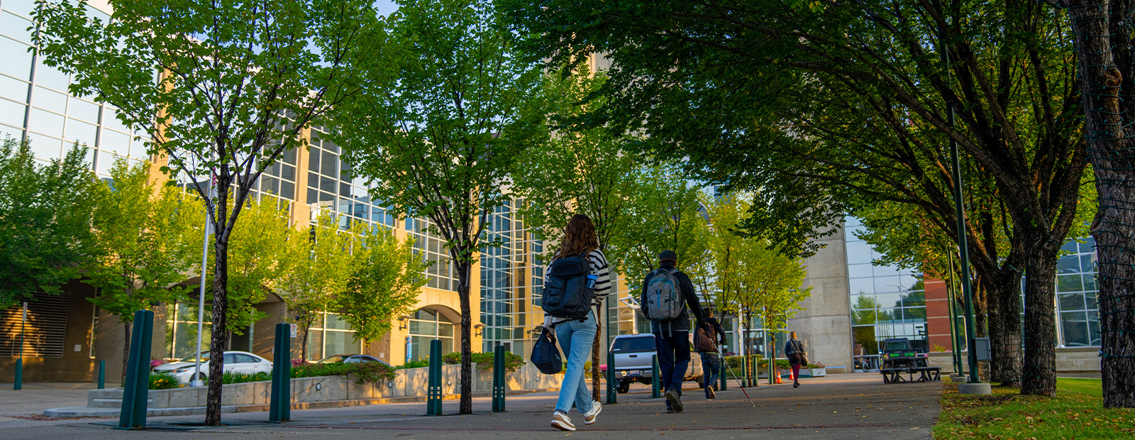 Two students walk toward MacEwan's clock tower entrance, carrying backpacks.