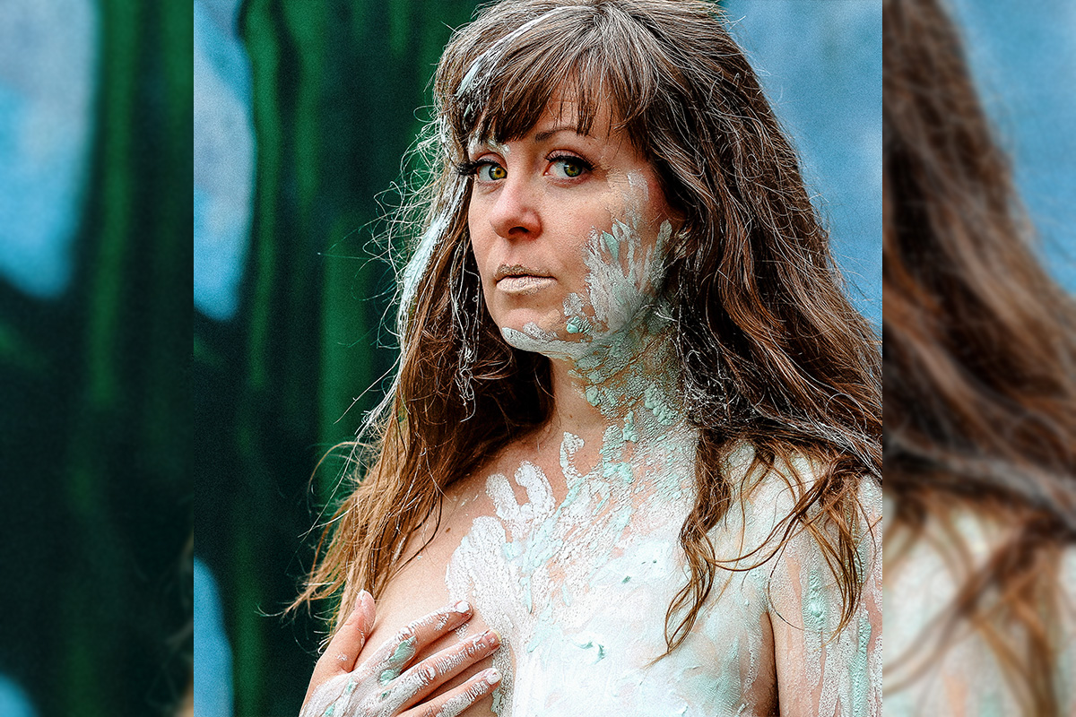 Ainsley Hillyard looks to the camera, her face, hands and neck covered in white and green paint