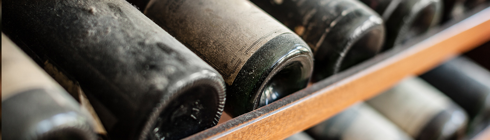 Dusty wine bottles on a wooden rack