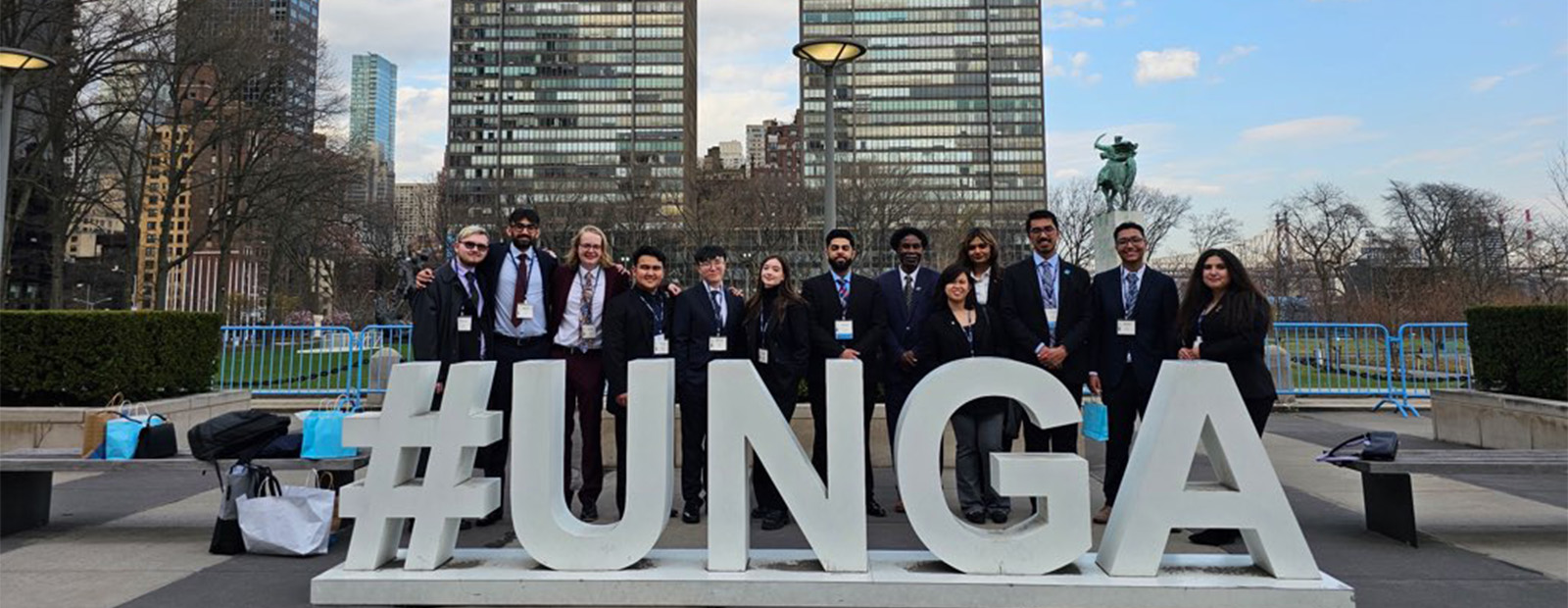 MacEwan students and faculty mentor Dr. Chaldeans Mensah stand behind a series of large letters that read "#UNGA"