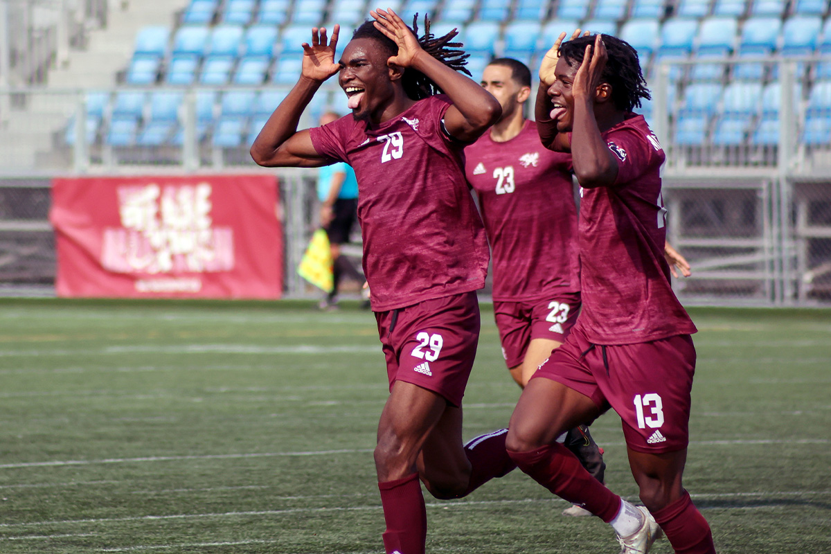 Masri and two teammates make goofy faces as they run on the soccer pitch.