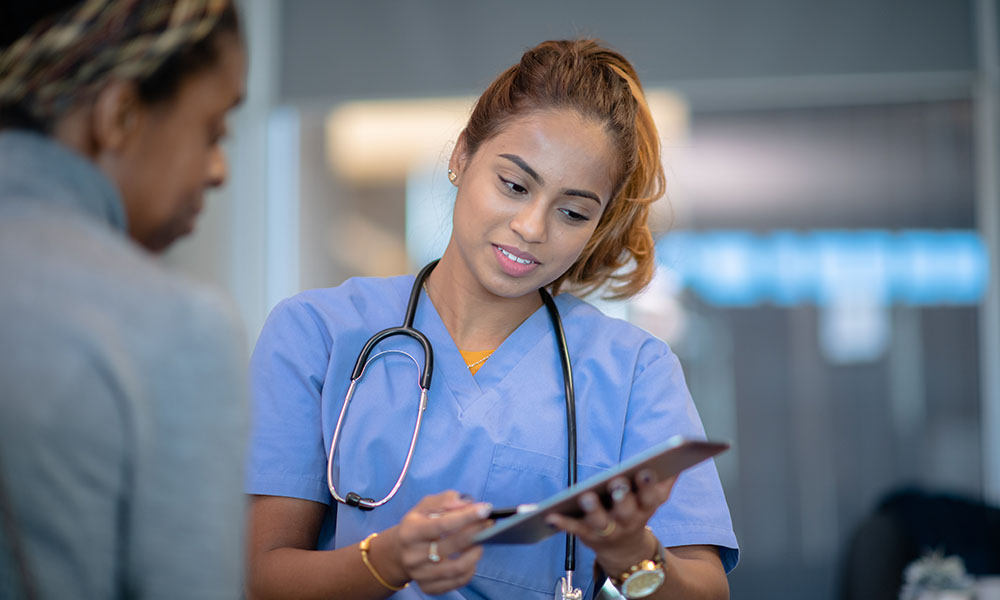 A nurse shows a patient information on a tablet