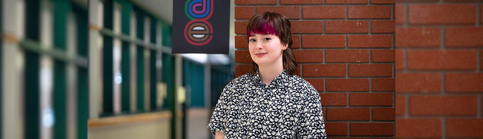 Alana Whitson stands in front of a Pride banner on campus