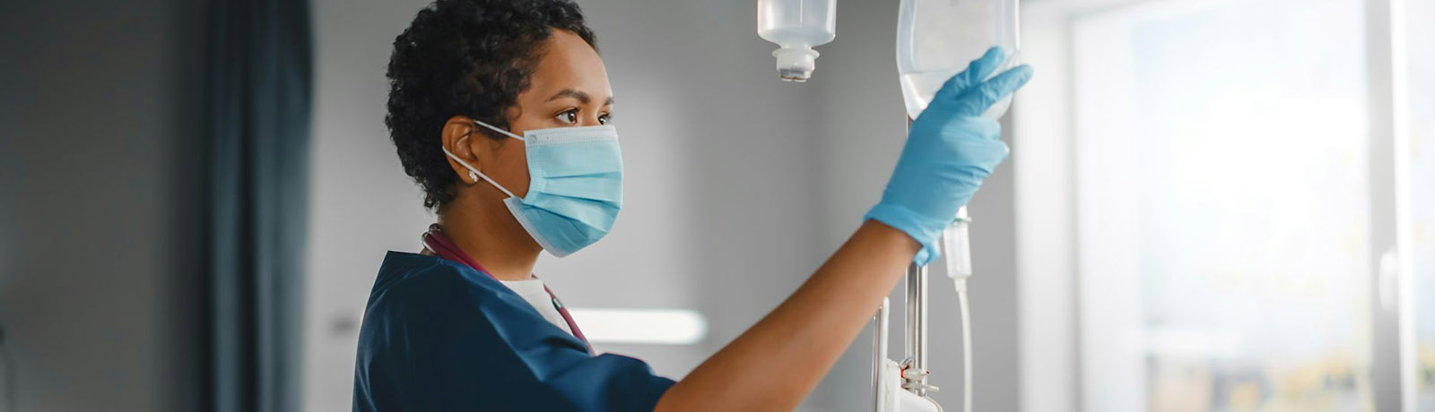 A nurse reaches toward an IV