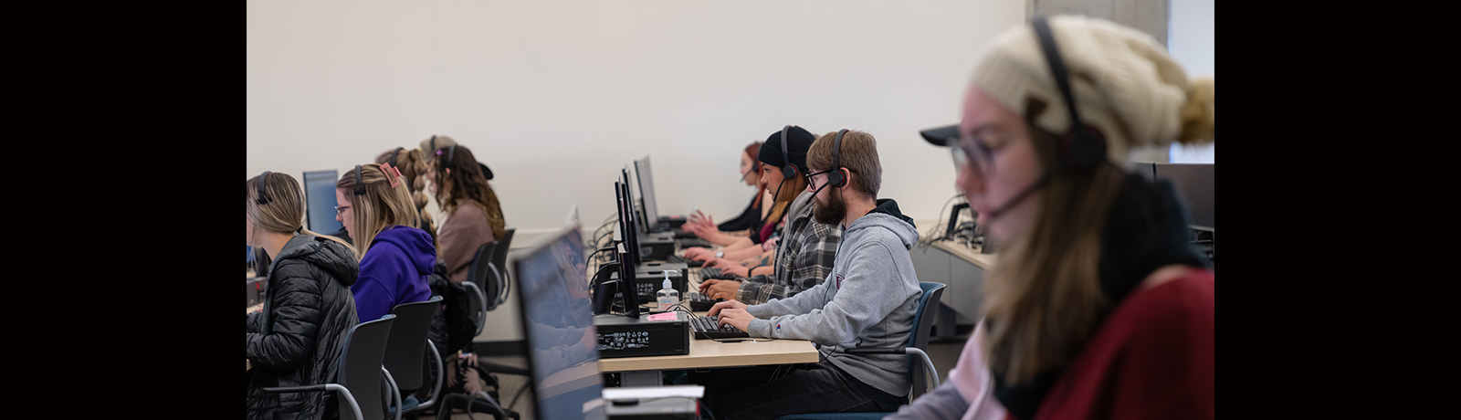 Image of students in front of laptops wearing headsets