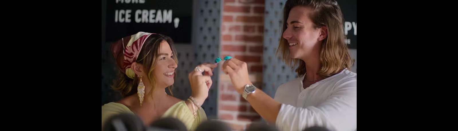 A couple smiles at each other at an ice cream shop