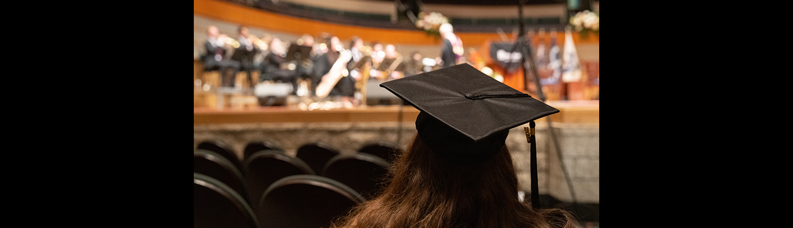 A graduating student, wearing a cap, sitting in the crowd at the Winspear Centre