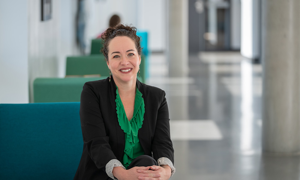 Dr. Melissa Hills wears a green shirt beneath a black blazer and smiles.