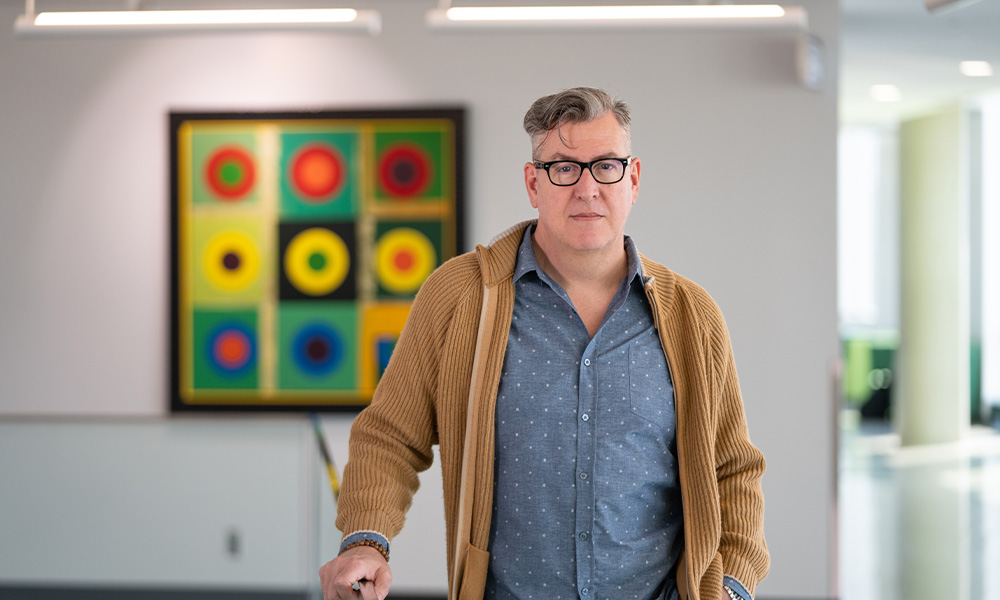 Wayne Williams stands against a glass railing in Allard Hall.