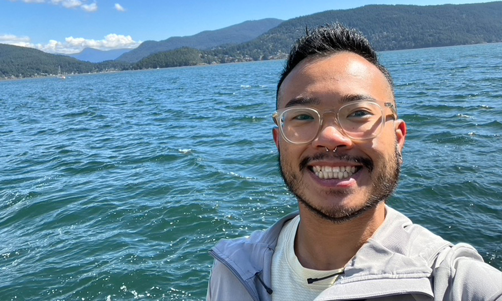 Wesley Tang smiles with the ocean in the background