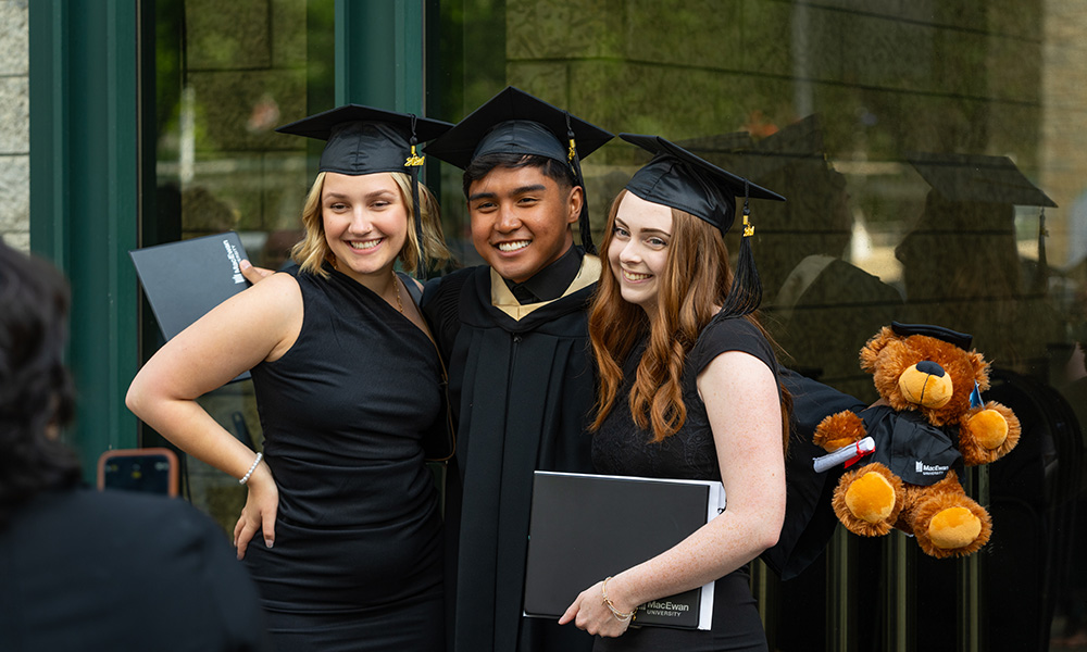 Three smiling women in black grad caps