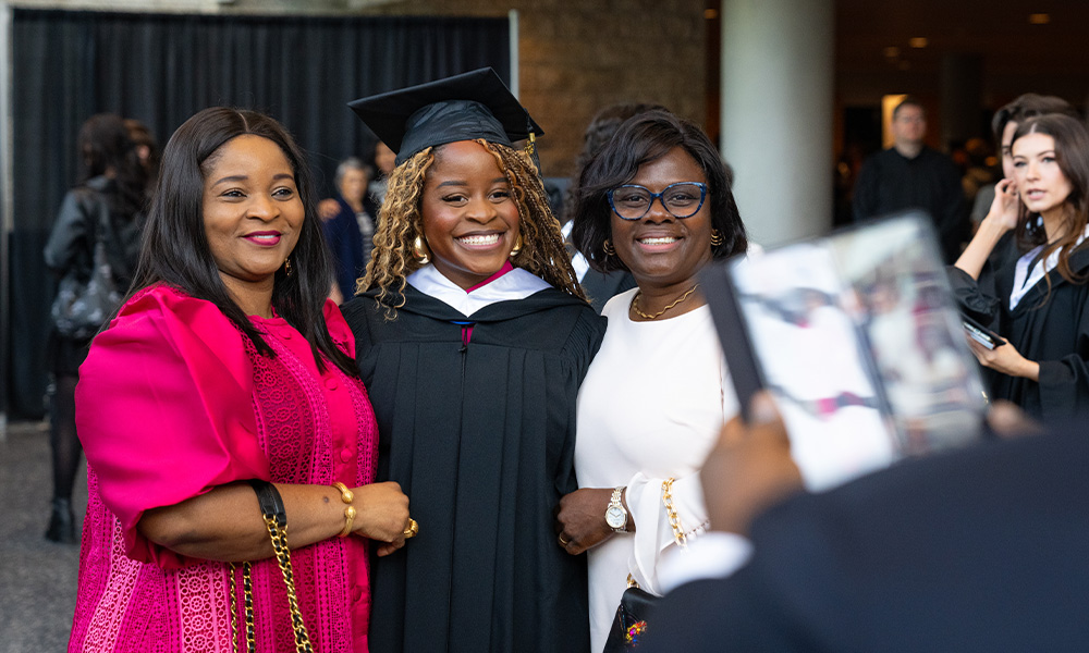 Three women stand smiling and holding their parchments