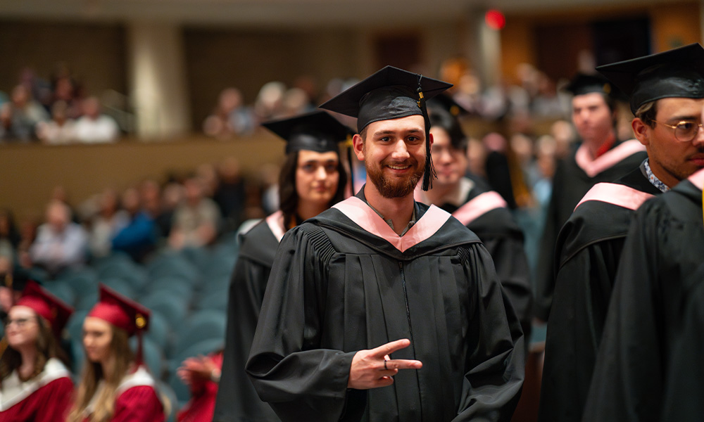 A grad walks down the aisle in the Winspear