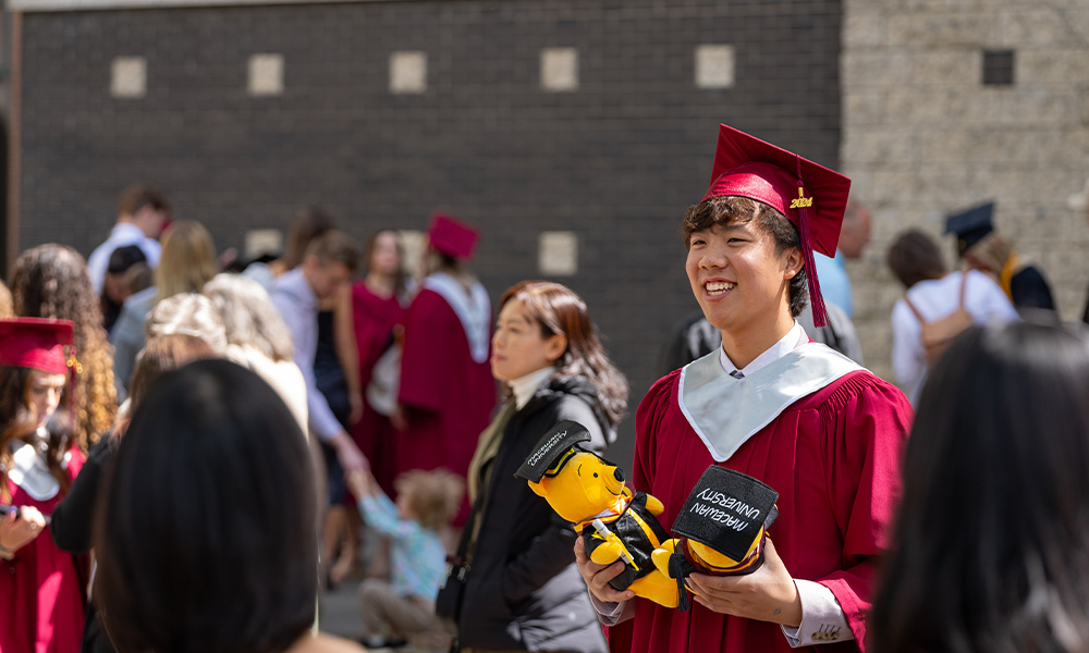 A smiling grad stands in a crowd