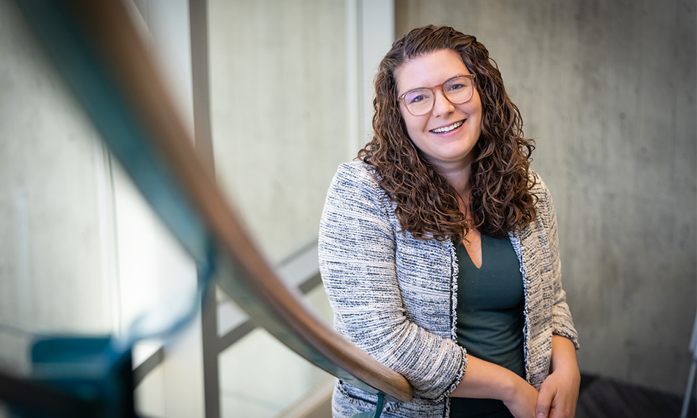 Dr. Kaitlin Towle leans against a railing inside the clocktower window in the library, smiling.