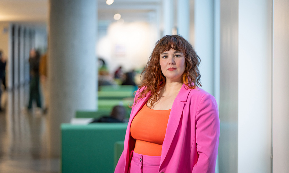 Marlene Wurfel stands in Allard Hall, wearing a pink blazer